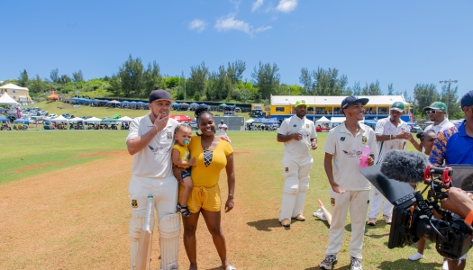 A woman and her child is posing with a cricket player at County Games.