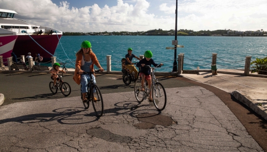A family is riding bicycles by the ferry in St. George's