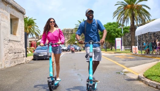 A man and a woman are riding electric scooters.