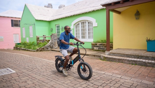 A guy is riding an electric bike down scenic St. George's.