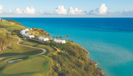 An aerial view of Port Royal Golf Course with a green fairway and blue, calm ocean. 