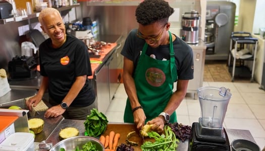 An older woman and young man are cooking in a kitchen.