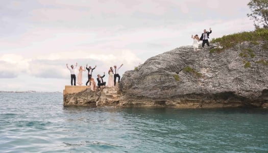 A couple if jumping off the rocks with their friends 
