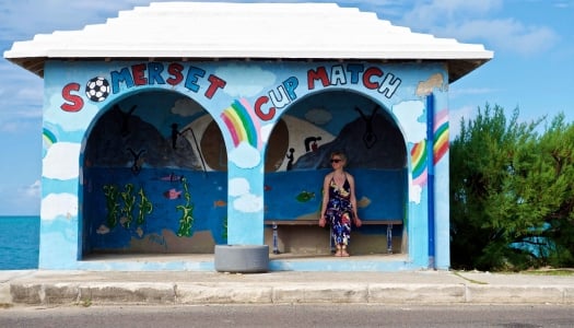 A woman is sitting a bus shelter.