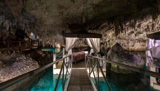 A floating dock with a massage table on it in a stunning cave in Bermuda.