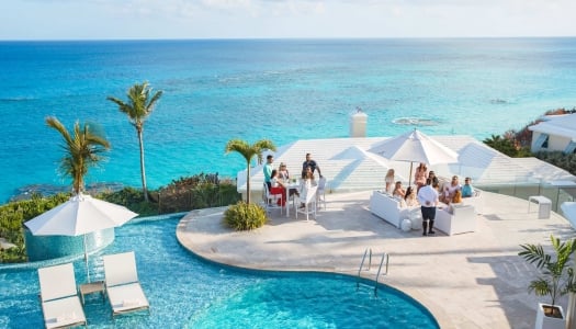 A group are sitting at a viewpoint with the ocean in the background.