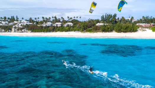 Two men are kite surfing in blue waters.