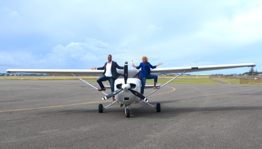 Two pilots are standing on a propeller plane.