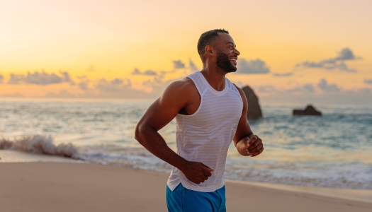 A man is running on the beach smiling.