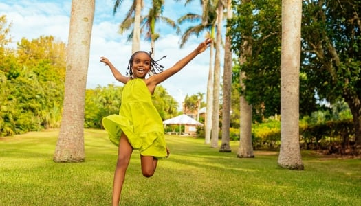 A little girl is running in the grass.