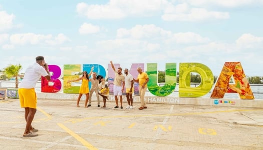 A group are posing in front of the Bermuda sign.