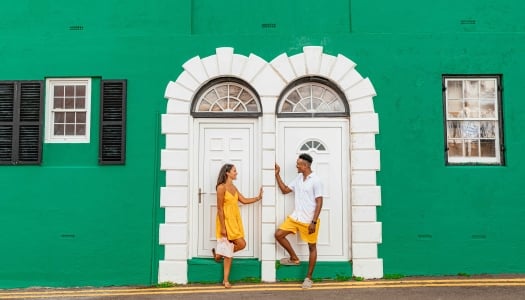 A couple is posing by a colourful building.