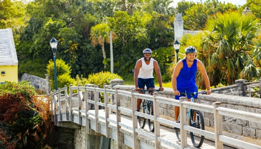 Two men biking by the smallest drawbridge.