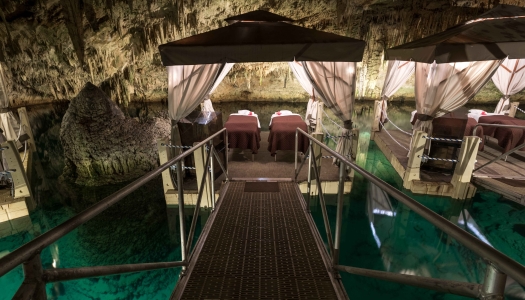 A couples massage beds on a floating platoon in a cave.