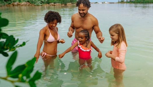 A family is in the water feeding fish.