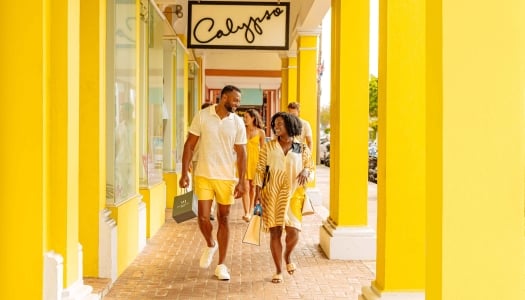 A couple are walking in hamilton by a bright yellow building.