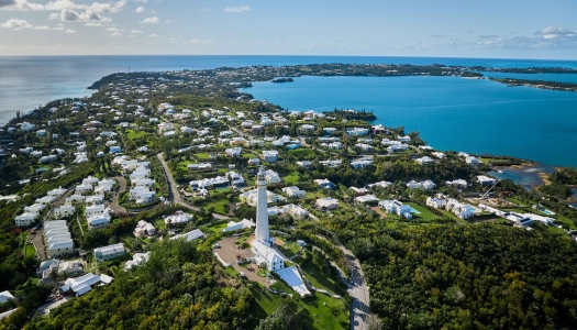 Aerial view of Gibbs Hill Lighthouse with calm waters and blue skies.