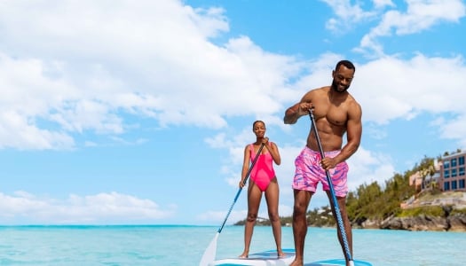 A couple are paddle boarding.