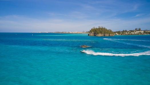 Two people are jetskiing by a shipwreck.