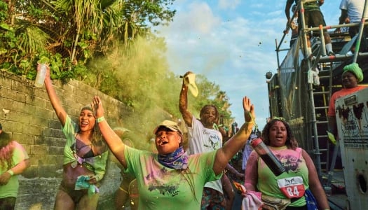 A group of people are smiling while paint is being thrown every where.