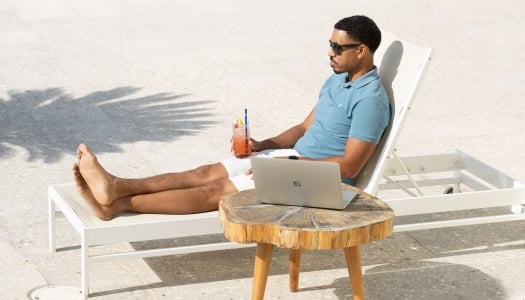 A man is sitting on a lounge chair by a lounge chat.