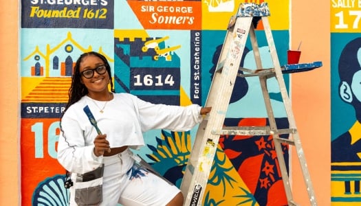A woman is smiling at the camera with paint brushes.