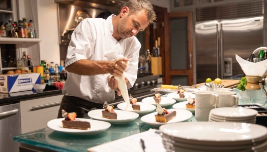 A chef is preparing plates during a private dinner.