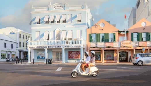 Two people are driving down Front Street on a Scooter