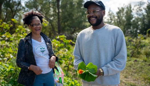 Two people are smiling holding plants