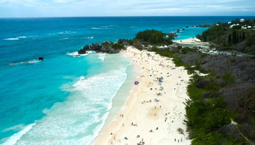 A beach is filled with people flying kites.