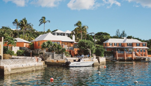 A waterview of an orange Bermuda house with a dock and boat.