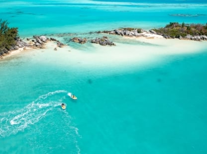 Aerial view of two jet skis riding close to a sandy shore