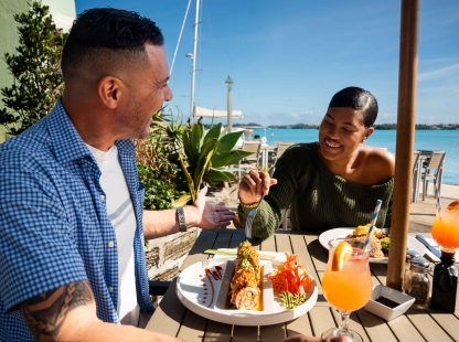 A couple are enjoying lunch at The Wharf by the water.