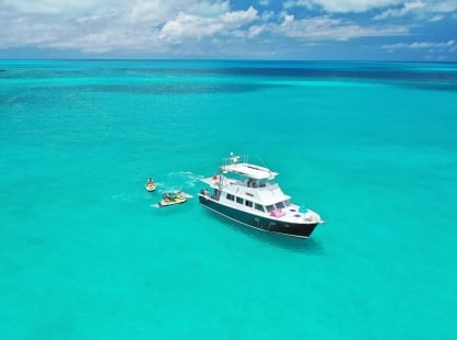 A boat on turquoise water near people on sea-doos 