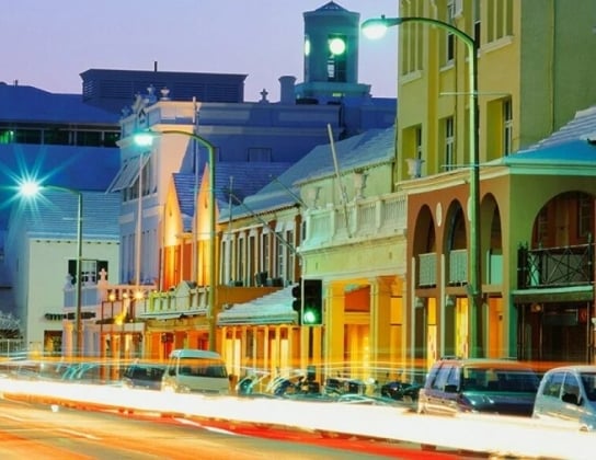Street view at night with cars parked on the side of the road
