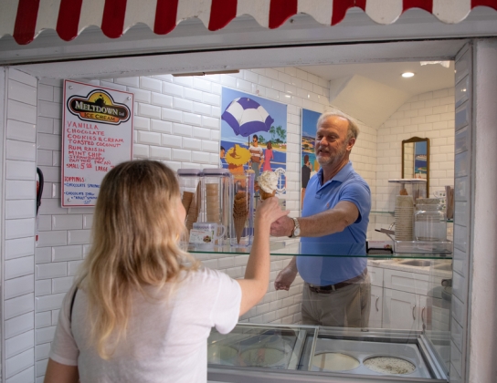 A man is handing an ice cream cone to a woman.