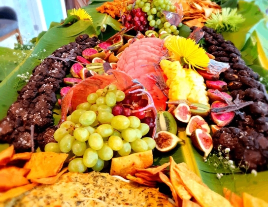 A colourful spread of fruits on a table covered in palm leaves.