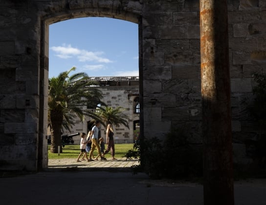 A long distance view of a family walking through old buildings in Dockyard.