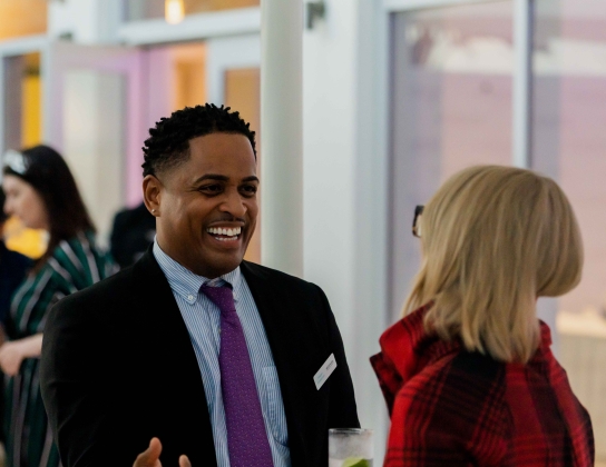 A man is smiling while talking to a woman.