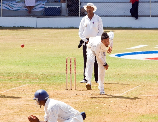 A man is bowling during a cricket game.