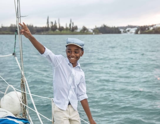 A little boy is smiling while walking on a boat.