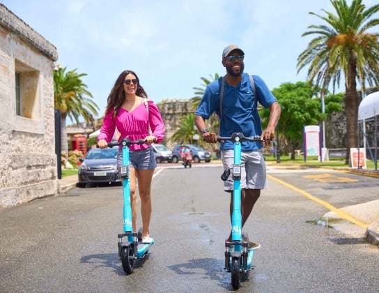 A man and a woman are riding electric scooters. 