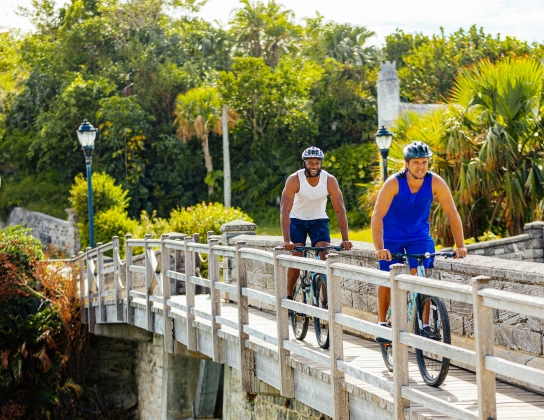 Two men biking by the smallest drawbridge.