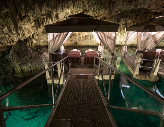 A couples massage beds on a floating platoon in a cave.