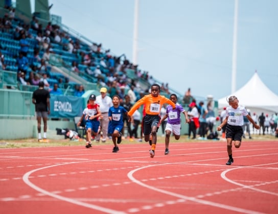 Little kids are running on a track.