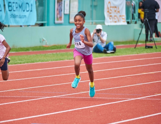 A little girl is running on the track.