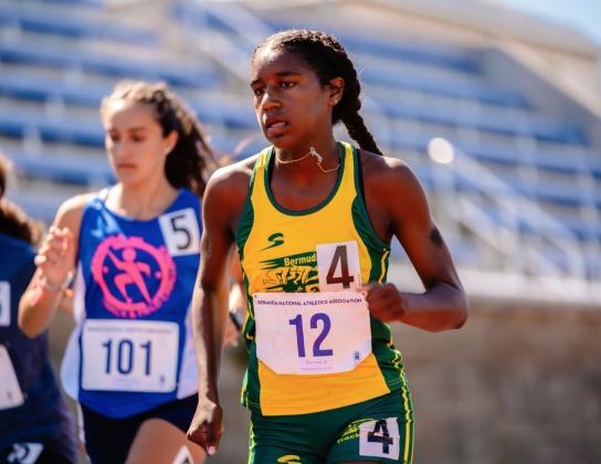 Three girls are running on a track.