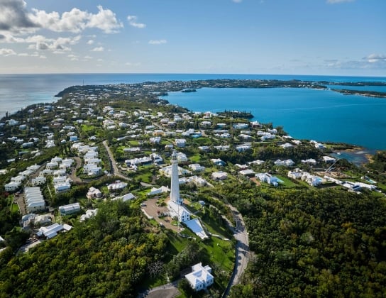 Aerial view of Gibbs Hill Lighthouse with calm waters and blue skies. 