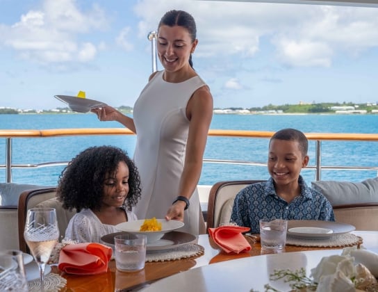 The server is serving kids food on a super yacht.
