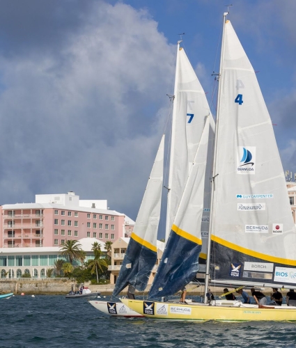 two sail boats sit anchored in front of a hotel